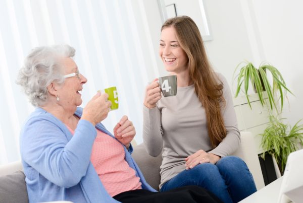 Ältere und jüngere Frau lächeln sich beim Kaffeetrinken an