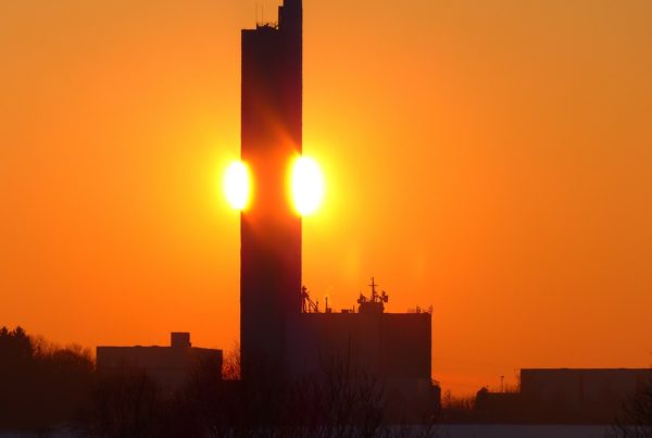 rot-oranger Himmel mit Sonnenuntergang im Hintergrund. Häuserumrisse im Vordergrund.